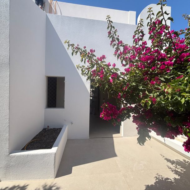 Whitewashed exterior stairs and courtyard of the Sunstone Terrace House, framed by bougainvillea
