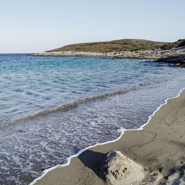 A quiet turquoise cove on Antiparos, clear shallow water meeting a sandy beach